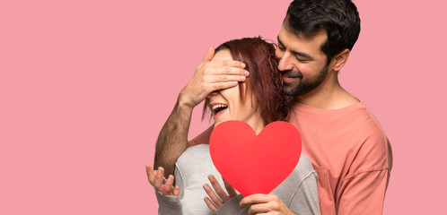 Fototapeta na wymiar Couple in valentine day holding a heart symbol over isolated pink background