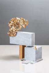 Installation using concrete blocks, textural building elements and a golden plant.