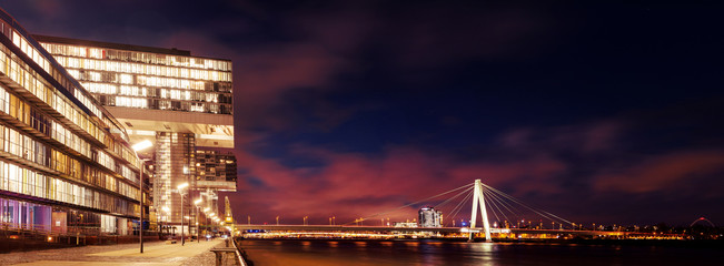 Panorama of the river side harbour with the crane house Kranhaus architecture and Severing Bridge Severinbrücke at night with colorful long exposure clouds. Köln, Cologne in Germany