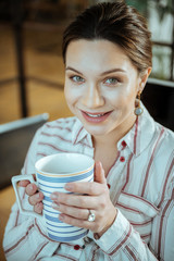 Pleasant woman enjoying her break from work drinking tea