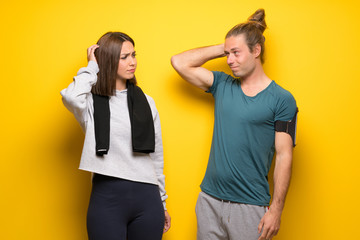 Group of athletes over yellow background having doubts while scratching head