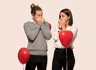 Couple in valentine day is a little bit nervous and scared putting hands to mouth over isolated background