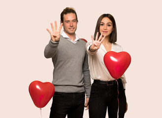 Couple in valentine day happy and counting four with fingers over isolated background