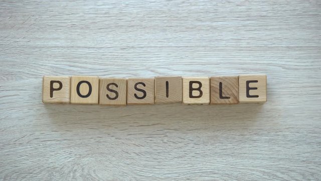 Possible, hand putting word on wooden cubes, possibilities, motivation and goals