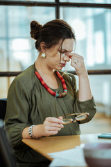 Dark-haired woman wearing stylish accessories feeling tired