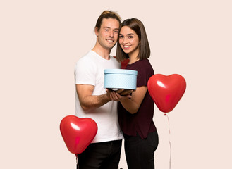 Couple in valentine day holding a gift in hands over isolated background