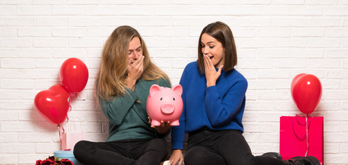 Couple in valentine day surprised while holding a piggybank