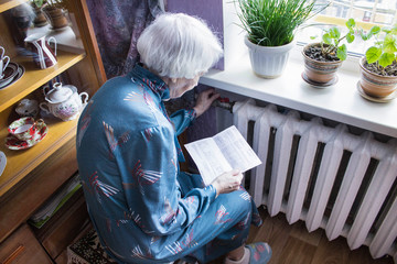 Woman holding cash in front of heating radiator. Payment for heating in winter. Selective focus.
