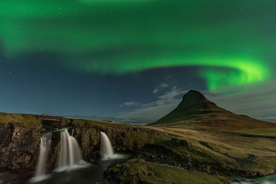 The Northern Light at the mountain Kirkjufell Iceland. Landscape of waterfall Kirkjufellsfoss, with green bands of Aurora Borealis. Snaefellnes, Iceland