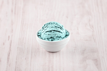 Scoop or mint ice cream in a bowl on awooden background