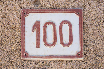House number one hundred. Red lettering on white background.