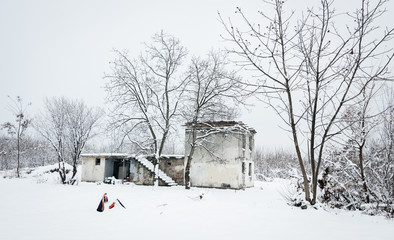 Old abandoned ruin house without windows and roof used as homeless shelter during the summer empty on the cold winter days with snow and low temperatures