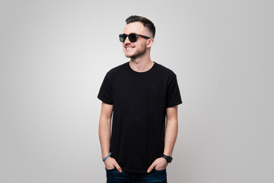 Portrait of cool  young gay in black tshirt and sunglasses. put hands in  pockets while looking away