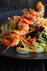 Shrimps on skewer with salad, avocado, tomato and pita chips