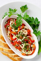 salad of marinated in lemon juice, garlic and olive oil calamary, bell pepper, and onion served with bread and decorated with parsley