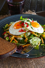 Fried eggs with avocado, salad leaves and crispy chips