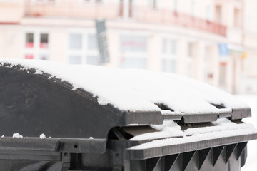 Trash bin on the winter street covered by snow