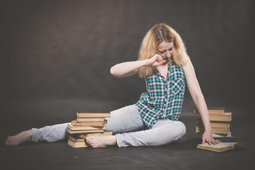 pretty young student girl sitting on the floor with books and very tired to learn