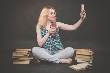 teen girl sitting on the floor next to books, does not want to learn, drinking juice and taking a...