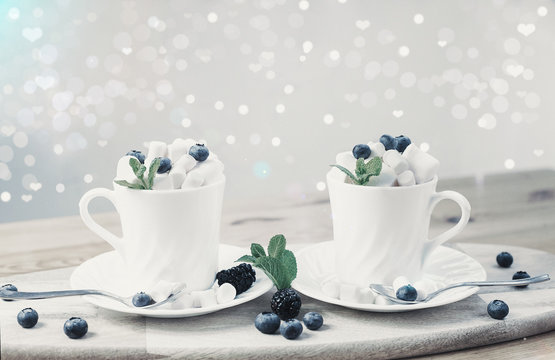 coffee with milk and marshmallows with blueberries and blackberries in white cups on wooden textured background. image