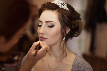 Make-up artist doing makeup to the bride on the wedding day. large portrait