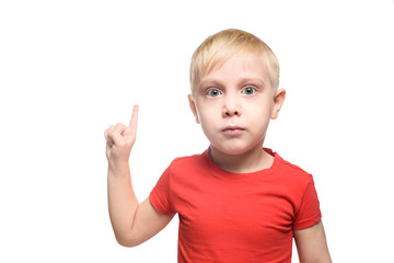 Surprised little blond boy in red t-shirt stands and points with index fingers upwards. Isolate on white bacground.