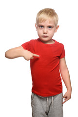 Fototapeta premium Blonde boy in a red shirt stands and shows index finger at yourself. Isolate on white background.