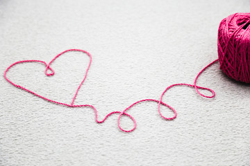 Pink heart of Pink wool yarn on a gray background
