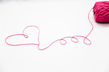 Pink heart of Pink wool yarn on a white background