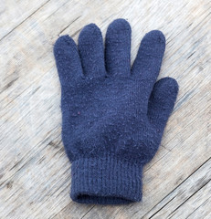 Closeup of lost or misplaced blue glove on wood bench.