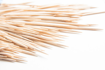 A bunch of unused round toothpicks from light-colored wood arrayed on a white plain background.