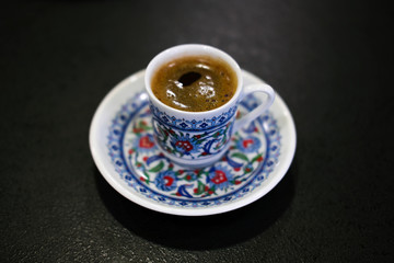 close up cup of Turkish coffee in traditional ottoman ornament cup isolated on black background 