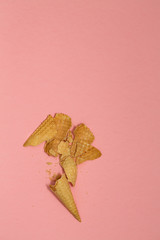 Crushed ice cream waffle cones on pastel pink background, top view flat lay, minimal composition. Place for text