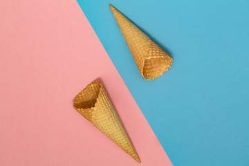 Ice cream waffle cones on pastel pink and blue background. Waffle ice cream cone. Top view. Flat lay. Modern minimal composition