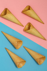 Ice cream waffle cones on pastel pink and blue background. Waffle ice cream cone. Top view. Flat lay. Modern minimal composition