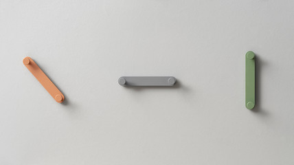 Fancy multicolored metal hangers on gray wall in studio