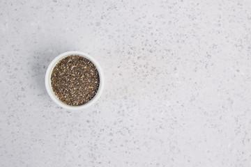 Small bowl with chia seeds seen directly from above on grey background