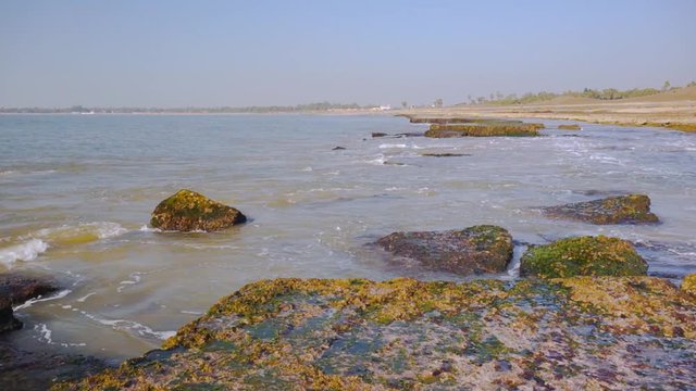 Waves dashing against the moss covered rocks on a beach in Diu, Gujarat, India