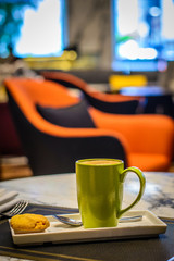 hot cafe latte with cookie on the side and a steel tea spoon