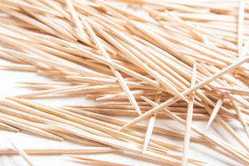 A bunch of unused round toothpicks from light-colored wood arrayed on a white plain background.