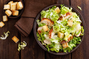 Caesar salad with grilled chicken meat, fresh lettuce, parmesan cheese and fried croutons. Classic North American cuisine. Top view - obrazy, fototapety, plakaty
