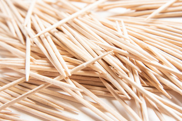 A bunch of unused round toothpicks from light-colored wood arrayed on a white plain background.