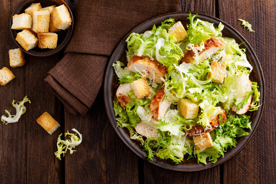 Caesar salad with grilled chicken meat, fresh lettuce, parmesan cheese and fried croutons. Classic North American cuisine. Top view