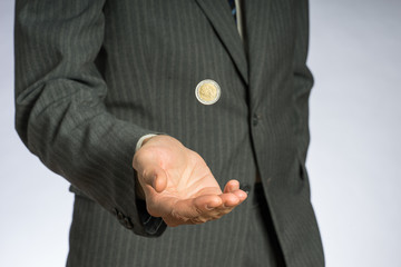 Business man with gray jacket throws up a euro coin. European finance currency.