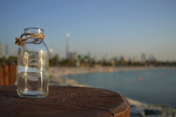 Obraz premium Szklany wazon na plaży, w tle panoramę Dubaju