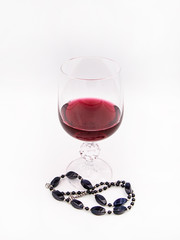 Glass of red wine with a black pearl necklace isolated on a white background