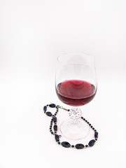 Glass of red wine with a black pearl necklace isolated on a white background
