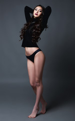 Studio portrait of sexy young woman. Beautiful girl dressed in black panties and jersey. Sensual lady against gray background. Full length