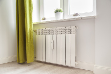 Heating white radiator radiator in living room. - obrazy, fototapety, plakaty