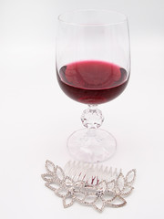 Glass of red wine with a silver hairpin with precious stones isolated on a white background